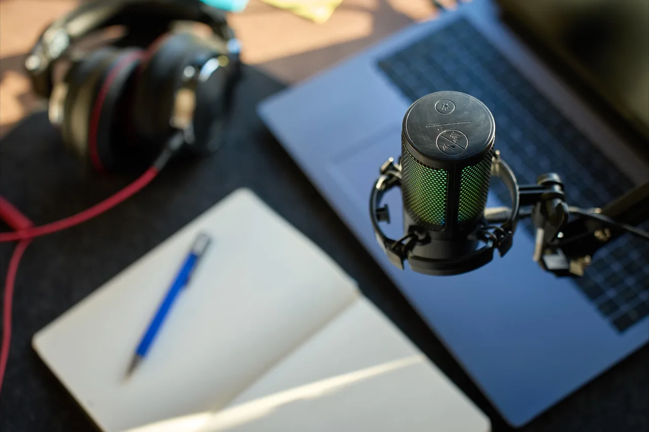 Microphone beside a notebook and headphones for a recording session